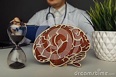 Wooden brain and hourglass in doctor& x27;s office close-up. Time and early diagnosis concept Stock Photo