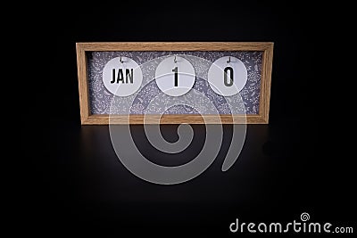 A wooden calendar block showing the date January 10th on a dark black background Stock Photo