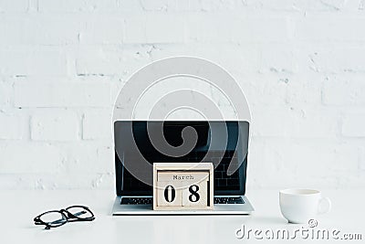 Wooden calendar with date of 8 march on laptop, international womens Stock Photo