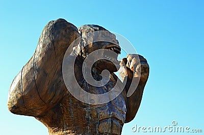 Wooden carved raging gorilla monkey statue, light blue clear skies in background. Editorial Stock Photo