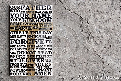 Wooden carved word of the Lord`s Prayer on the grey concrete background. Stock Photo