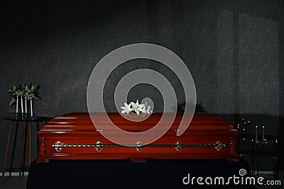 Casket with white lilies and burning candles in funeral home Stock Photo