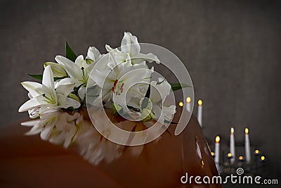 Wooden casket with white lilies in funeral home Stock Photo