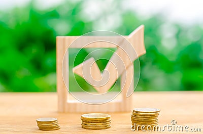 Wooden check mark and stacks of coins. Interest rates on deposits and loans. Lobbying the adoption of regulations and laws. Stock Photo