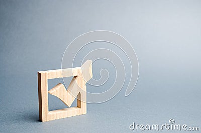 Wooden checkmark for voting on elections on a gray background. Presidency or parliamentary elections, a referendum. Survey of the Stock Photo