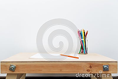 Wooden child drawing table with color pencils by the white wall Stock Photo