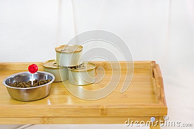 a wooden coffee tray with dry and canned cats food and a red candle on the white background Stock Photo