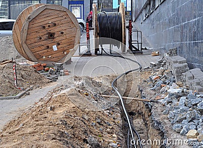 Wooden coil of electric cable and optical fibres in the digging on the street Stock Photo