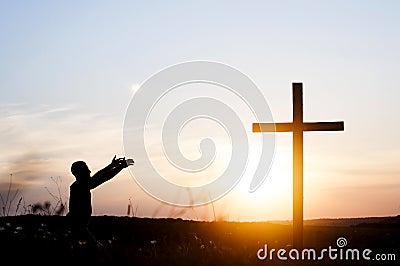 Wooden cross against the sky. The silhouette of the cross. A man is praying with his hands up. Motiveva on her knees. Sunset Stock Photo