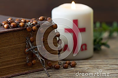 Wooden cross with bible, rosary and paschal candle, easter religious concept Stock Photo