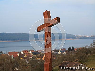 Wooden cross at pilgrimage route by lakeside village Stock Photo