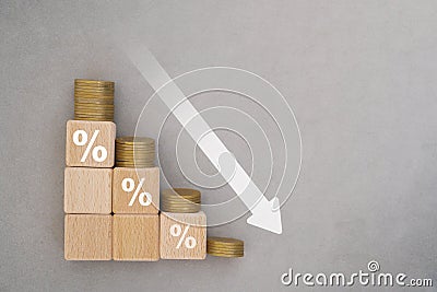 Wood cube block with percentage sign and down arrow with stack of coins. For financial recession crisis, interest rate decline Stock Photo