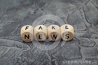 Wooden cube with word FAKE NEWS on dark background Stock Photo