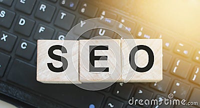 Wooden cubes with the acronym SEO for search engine optimization put on computer keyboard. Online business projects copywriting Stock Photo
