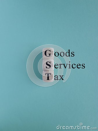 Wooden cubes with letters GST -goods and services tax on a blue background. State financial policy to regulate tax collection Stock Photo