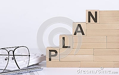 Wooden cubes with letters PLAN on the white table with keyboard and glasses Stock Photo