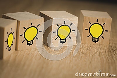 Wooden cubes standing above each other with the image of a burning lamp, which symbolizes the new idea, the concept of innovation Stock Photo