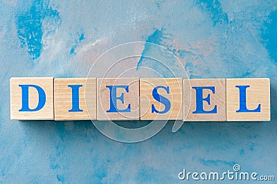 Wooden cubes with word DIESEL on blue table. Stock Photo