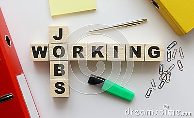 Wooden cubes with words JOBS WORKING on the office desk. Folder and other office supplies Stock Photo