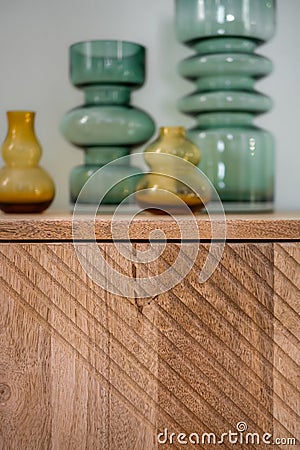 Wooden cupboard with decorative vases from transparent glass of green and yellow color Stock Photo