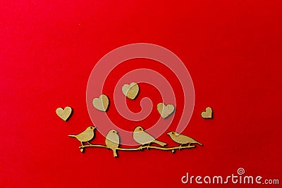 Wooden decoration flock of enamored birds sitting on a branch and wooden hearts around birds on a red background. Copy space. Stock Photo