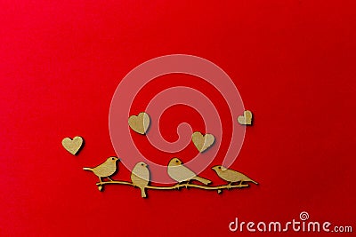 Wooden decoration flock of enamored birds sitting on a branch and wooden hearts around birds on a red background. Copy space. Stock Photo