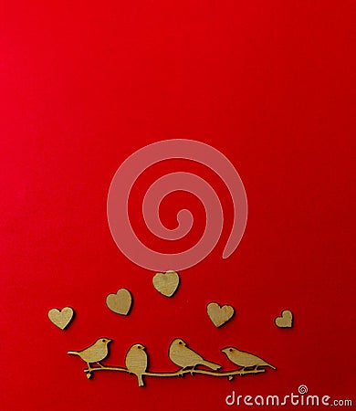 Wooden decoration flock of enamored birds sitting on a branch and wooden hearts around birds on a red background. Copy space. Stock Photo