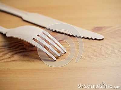 Wooden degradable fork and knife on a light wood table surface, Stock Photo
