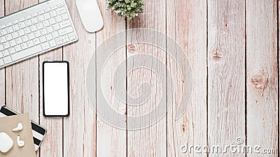 Wooden desk workplace with blank screen smartphone, keyboard, mouse, earphone and notebook, Stock Photo