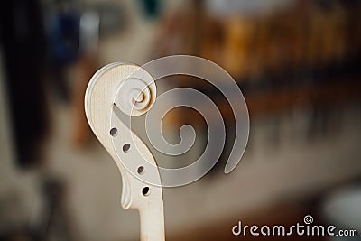 Wooden detail of the head of the violin. Raw wood, texture. Against the background of workshop. Stock Photo