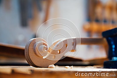 Wooden detail of the head of the violin. Raw wood, texture. Against the background of workshop. Stock Photo