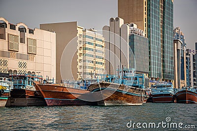 Wooden dhow cargo boats in Dubai Creek, modern buildings in the background, UAE Editorial Stock Photo