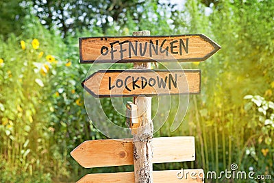 Wooden direction sign with the German word Ã–ffnungen openings and Lockdown Stock Photo