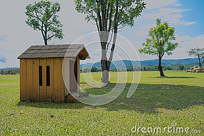 The wooden dog house is in a meadow with large trees Stock Photo