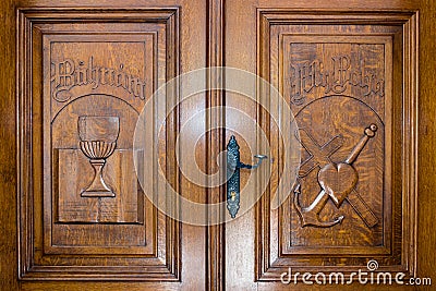 Wooden door with christian symbols: Bible, medieval cup, heart, cross and anchor Stock Photo