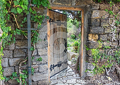 Wooden door decorated with iron forging, slightly open. Wall of Stock Photo