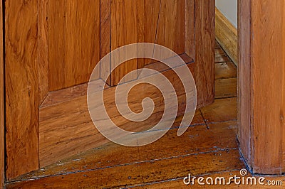 A wooden door stands slightly open offering a glimpse of the hall behind Stock Photo