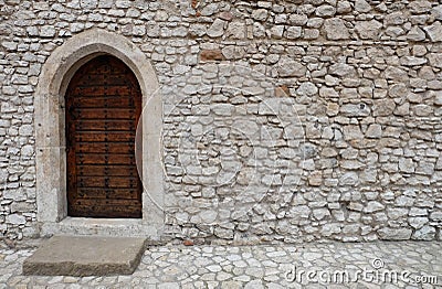 A wooden door with pointed gothic style arch in a stone wall Stock Photo