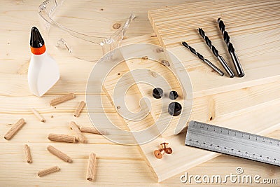 Wooden dowel joint pins drill glue wood planks safety glasses and tools spruce background. Carpenter industry funiture making Stock Photo