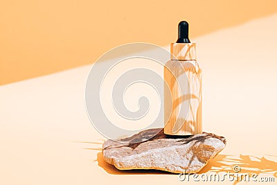 Wooden dropper bottle with cosmetic oil or face serum under sunlight with leaves shadows on it Stock Photo