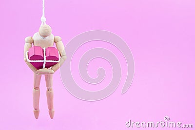 Wooden dummy chaining themselves to the paper box red heart shape on pink background with copy space for your Stock Photo