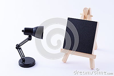 Wooden Easel Miniature with Blank Black Square Canvas and Table Lamp Stock Photo