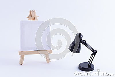 Wooden Easel Miniature with Blank White Square Canvas and Table Lamp Stock Photo