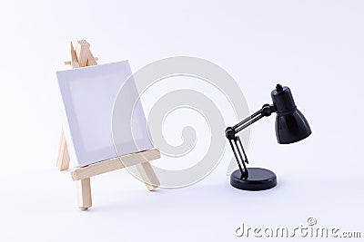 Wooden Easel Miniature with Blank White Square Canvas and Table Lamp Stock Photo