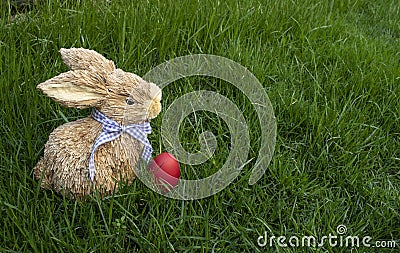 Wooden Easter bunny with red egg on real grass background Stock Photo