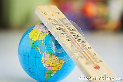 Wooden eco-friendly thermometer and globe on the background of a room or classroom interior. Stock Photo
