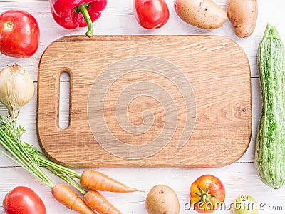 Wooden empty chopping board and vegetables near. Stock Photo