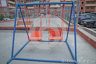 Wooden and Empty red and blue chain swings in children playground . chain swings hanging in garden . Childs swing in a park Stock Photo