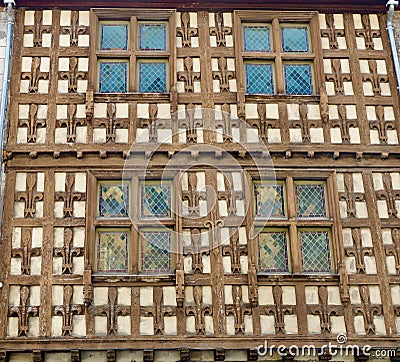 Wooden facade of medieval building with french royal symbolics and tiny mosaic windows. Rustic decadence in Arreau, France Stock Photo
