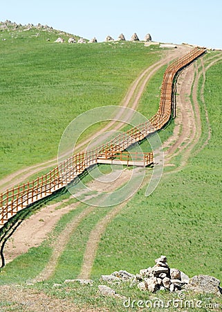 Wooden fence on lush green hillside Stock Photo